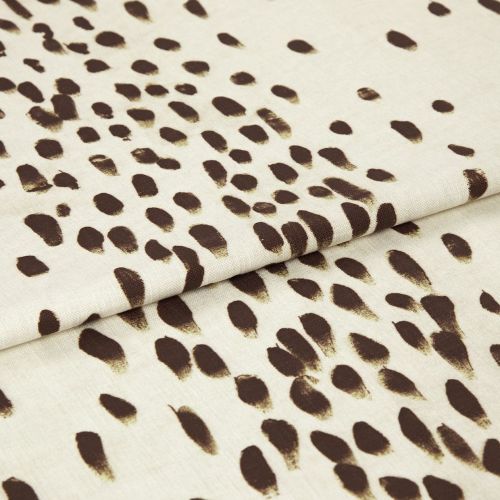 Beige woven fabric with irregular dark-brown brushstroke spots, folded once with a visible overlap; close-up studio view showing texture and soft, even lighting on a neutral background.