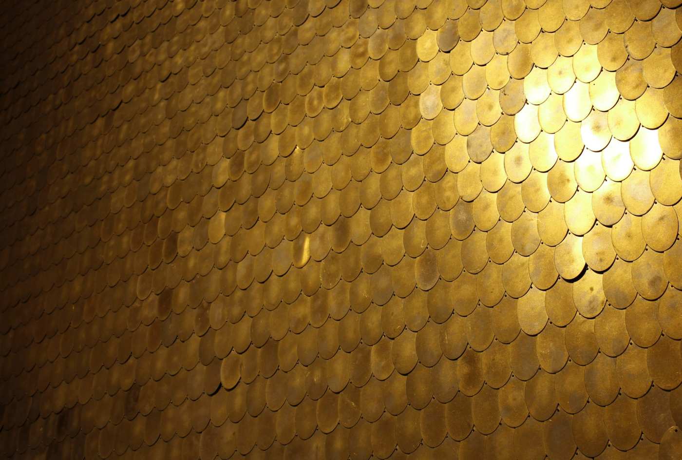 a gold tiled wall in a dark room.