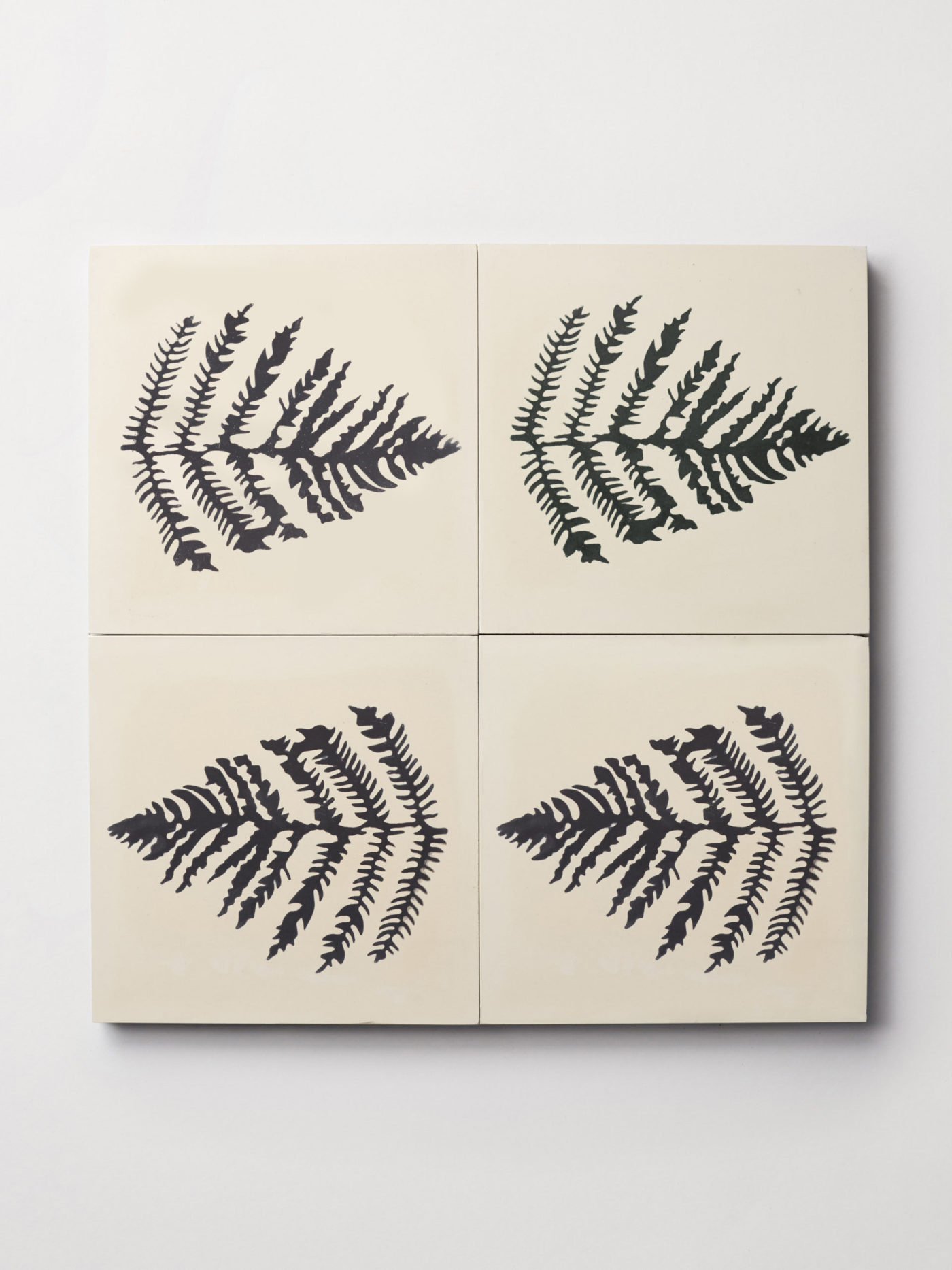 four black and white tiles with prints of fern leaves on them.