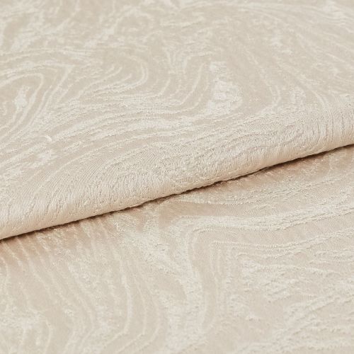 Beige jacquard fabric with subtle swirling embossed pattern, folded over itself; close-up view showing raised texture and soft sheen, neutral lighting on a plain surface.