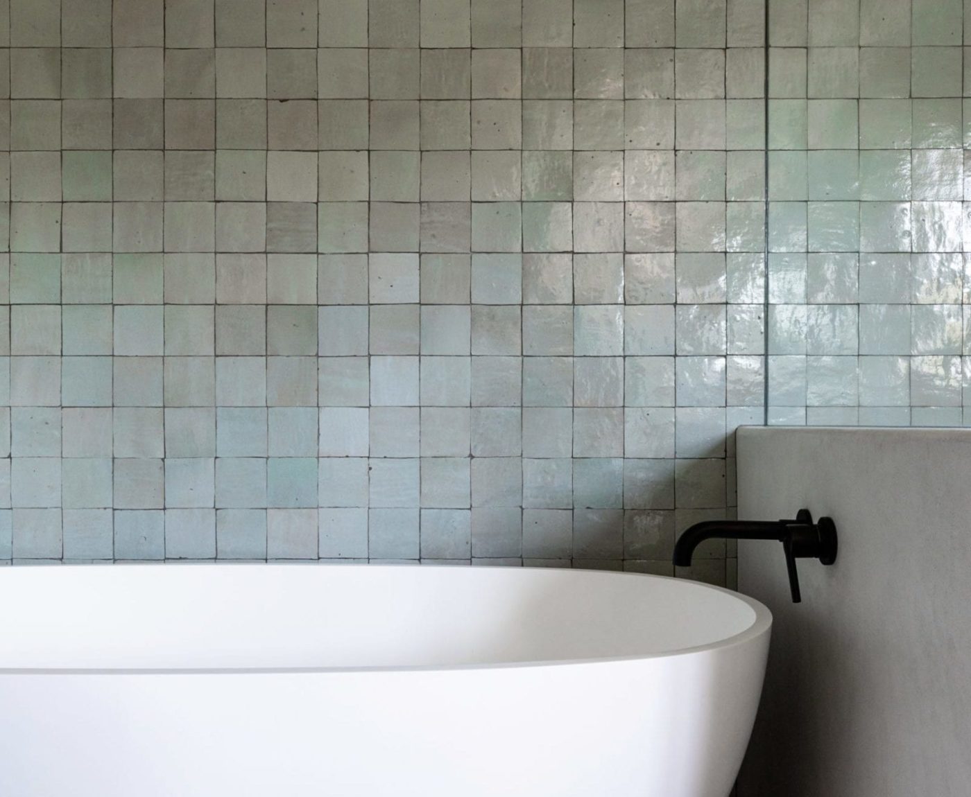 a white bathtub sits in front of a tiled wall.