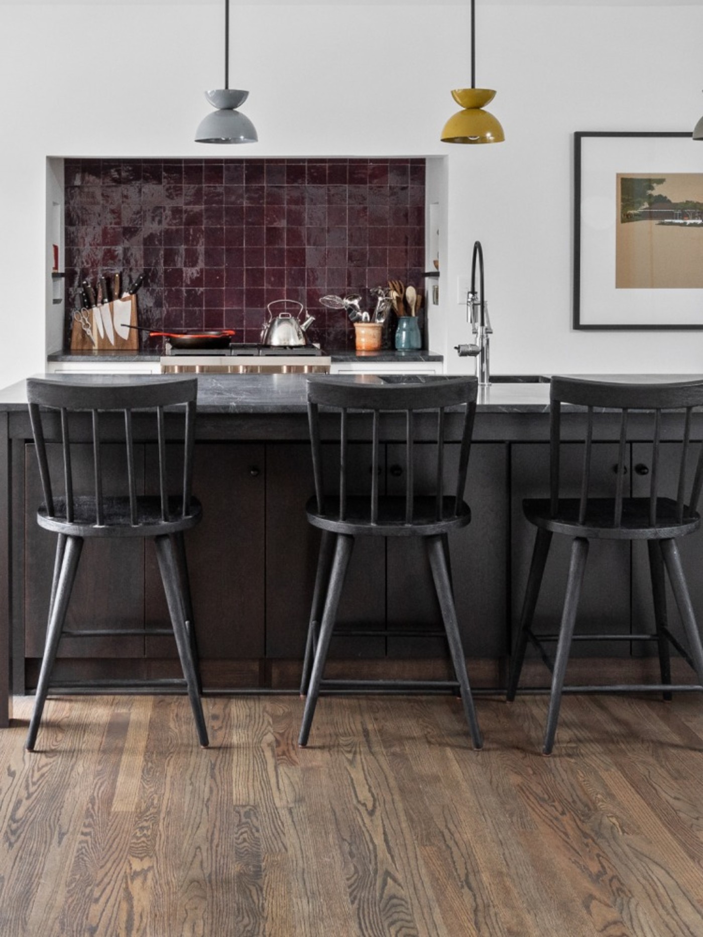 a kitchen with wooden floors and black stools.