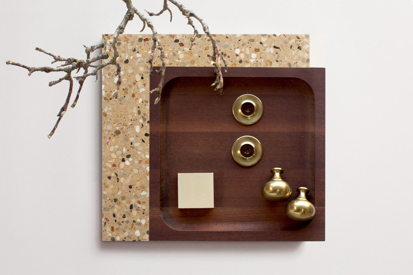 a wooden tray on a terrazzo tile with a branch hanging from it.