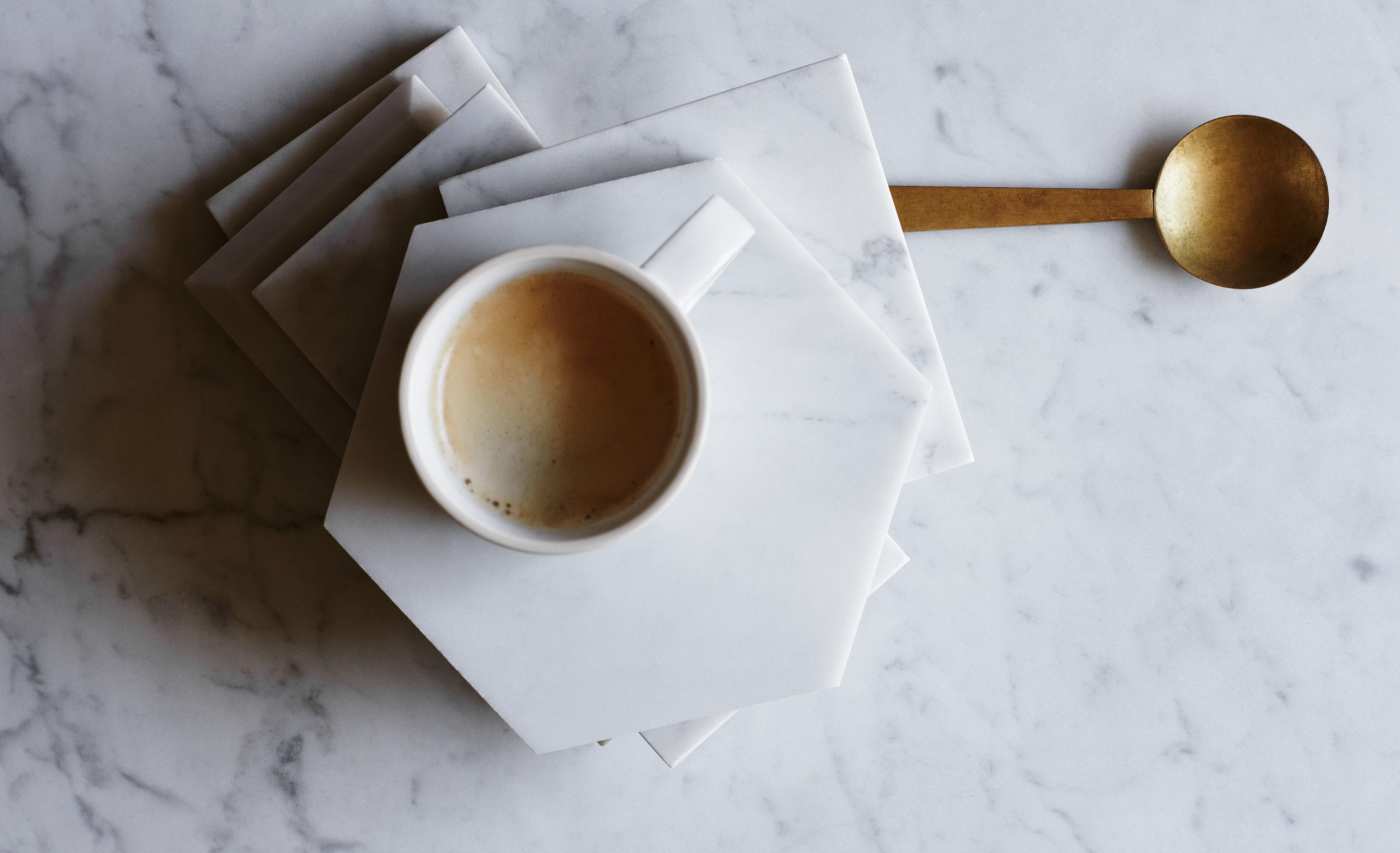 a cup of coffee sitting on a stack of marble tiles.