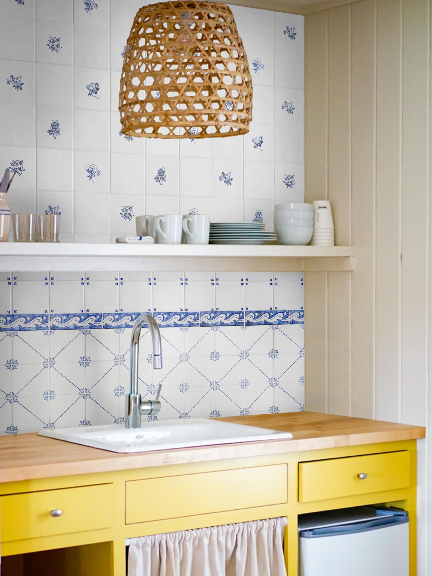 a kitchen with yellow drawers and a blue and white tiled sink backsplash.