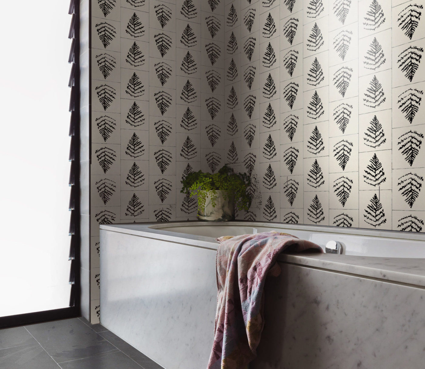 a bathroom with a black and white tiled wall with designs of fern leaves.