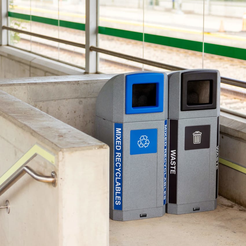waste and mixed recyclables bins with canopy lids and color coded labelling at a train station