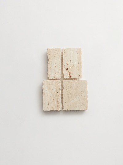 four squares of travertine on a white surface.