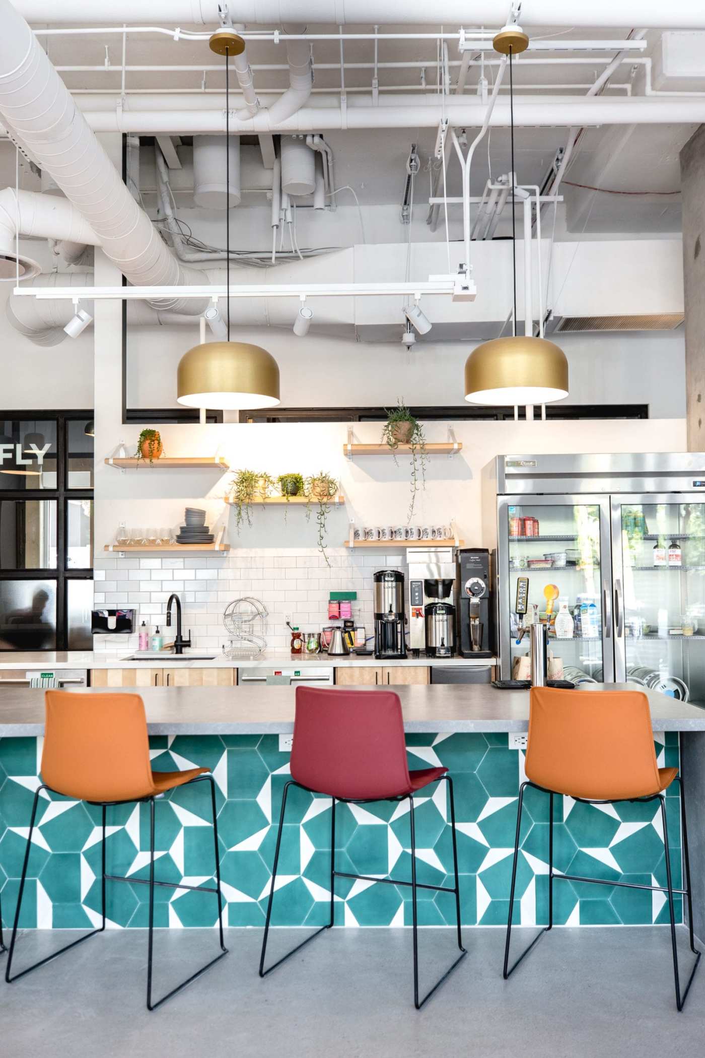 an office with colorful chairs and a blue and white tiled kitchen counter.