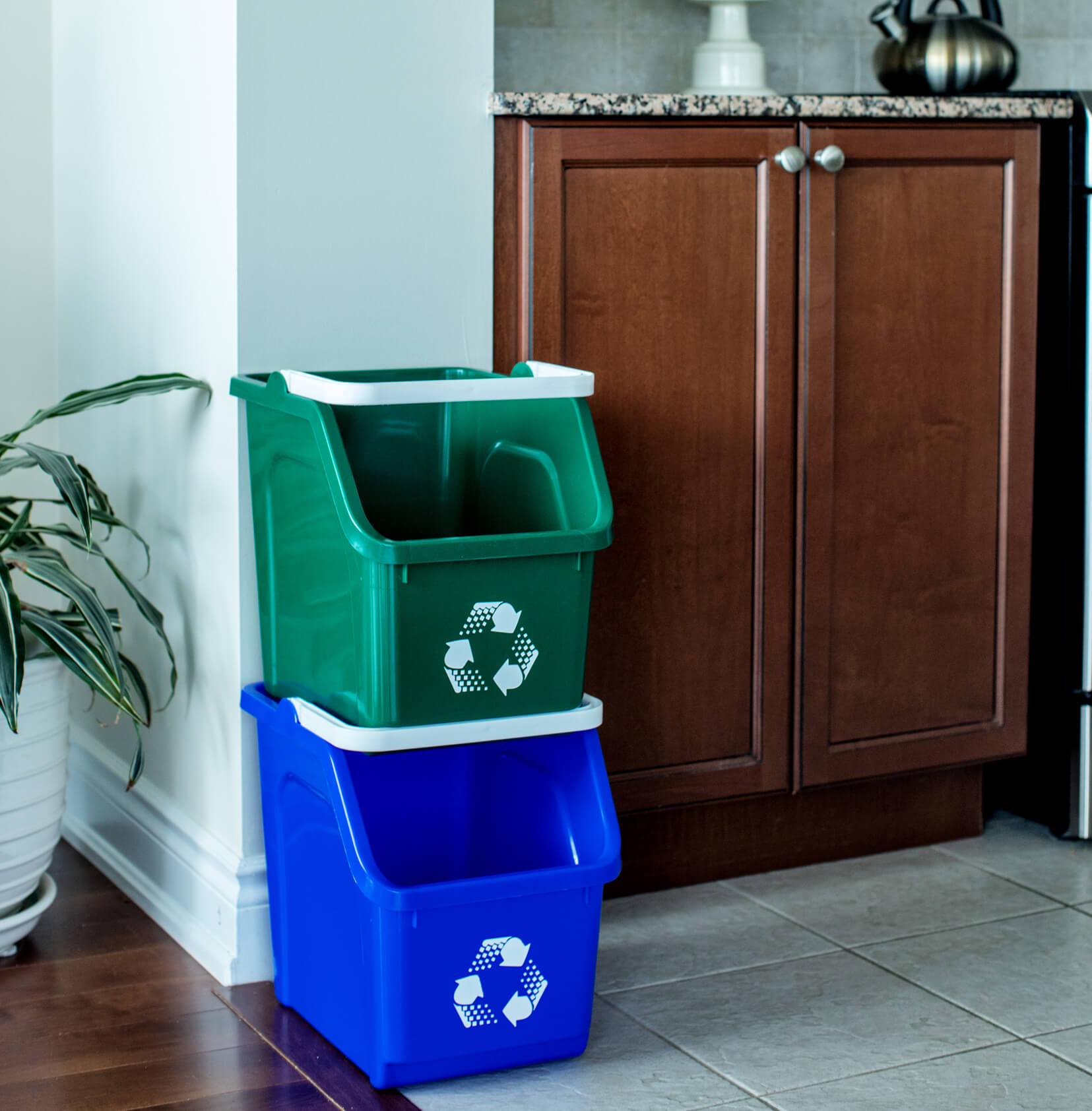 blue and green plastic stackable recycling containers in a residential kitchen area sitting on the floor