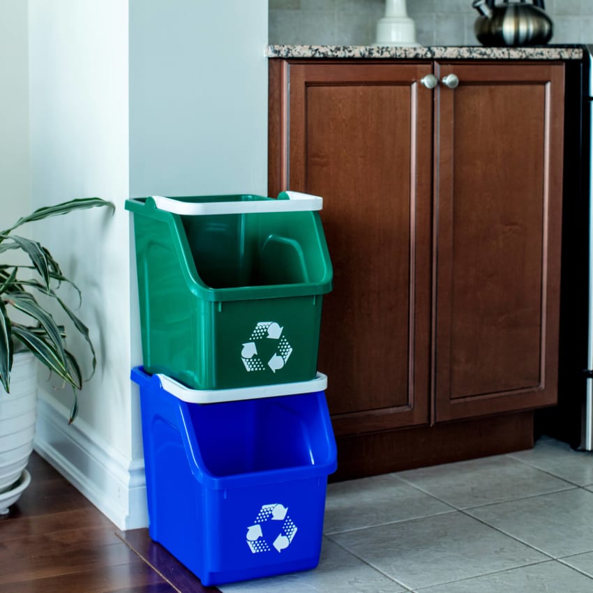 blue and green plastic stackable recycling containers in a residential kitchen area sitting on the floor