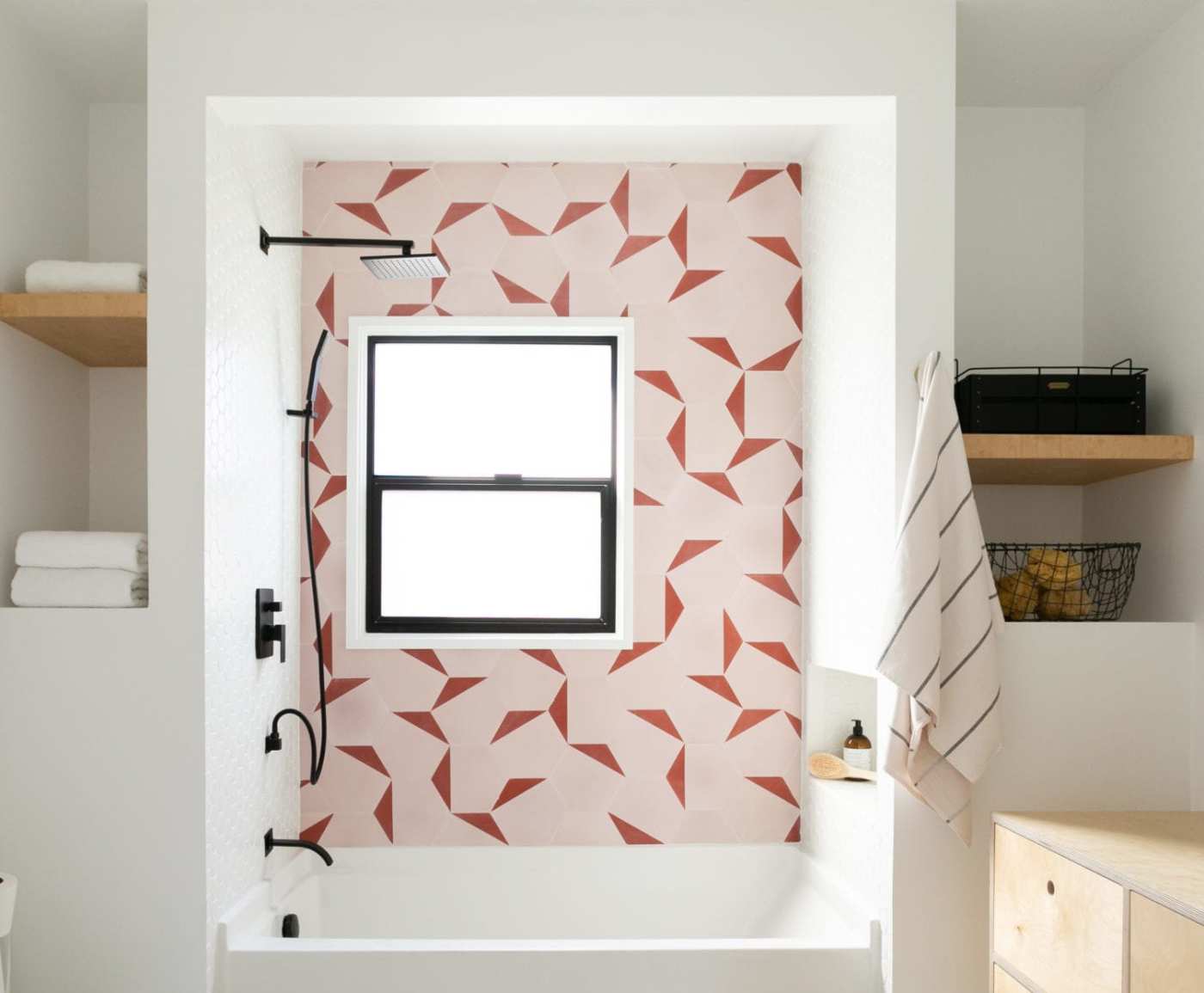 a bathroom with a pink and red tiled wall.