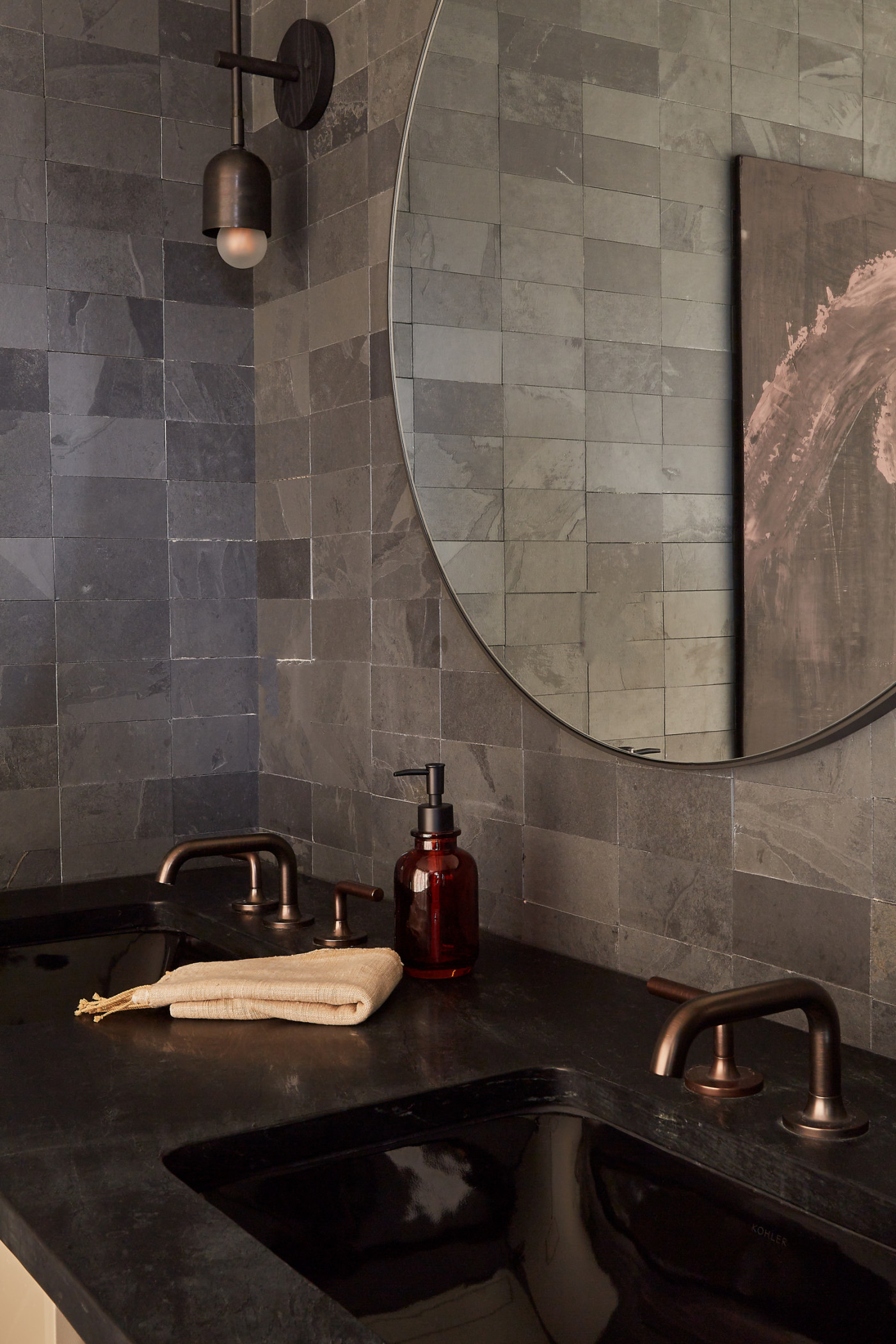 a bathroom sink with a grey tiled backsplash and a mirror above it.