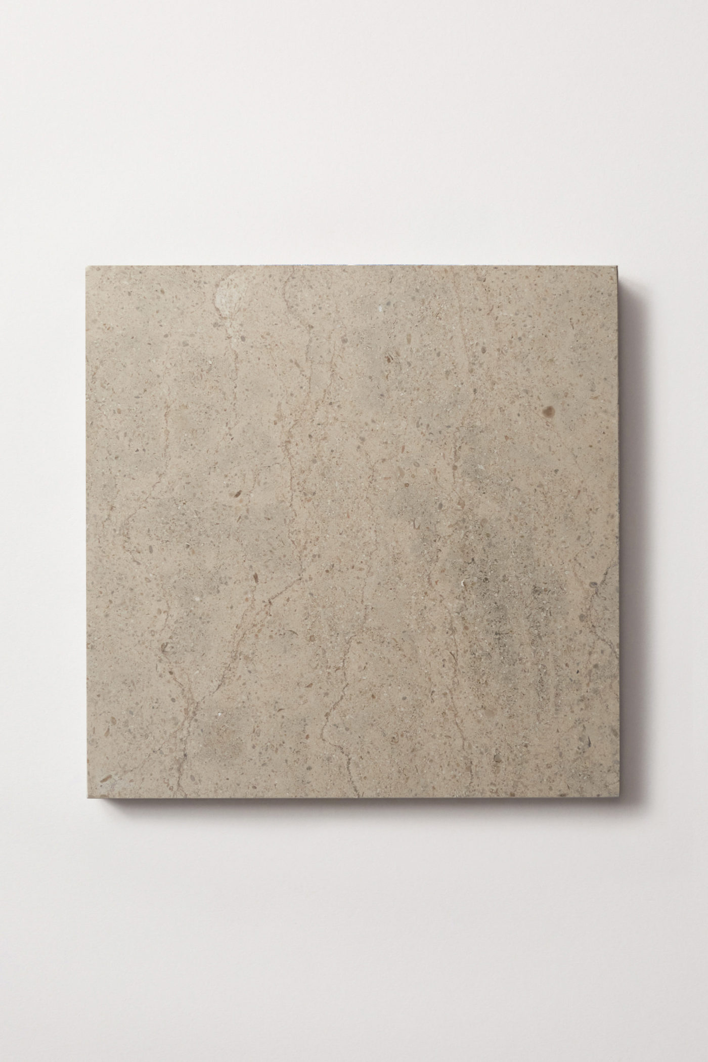 a square limestone tile in medium-grey beige color, marked striations and flecks of white.