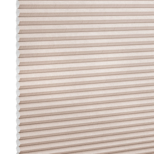 Beige honeycomb cellular blind with horizontal pleats and textured fabric, fully lowered and closed, diffusing light across a neutral, softly lit interior close-up.