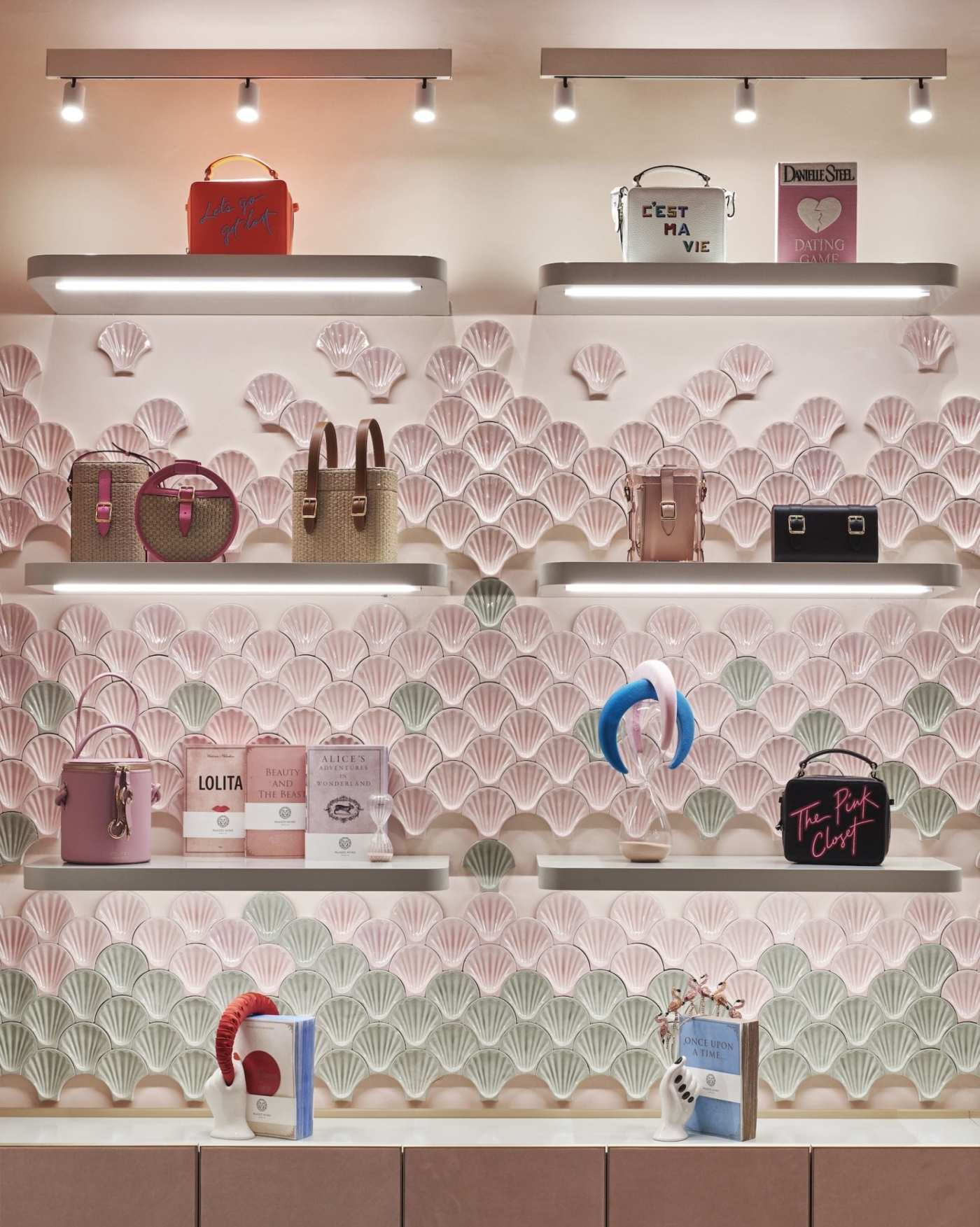 a display of items on shelves on a pink and green tiled wall.