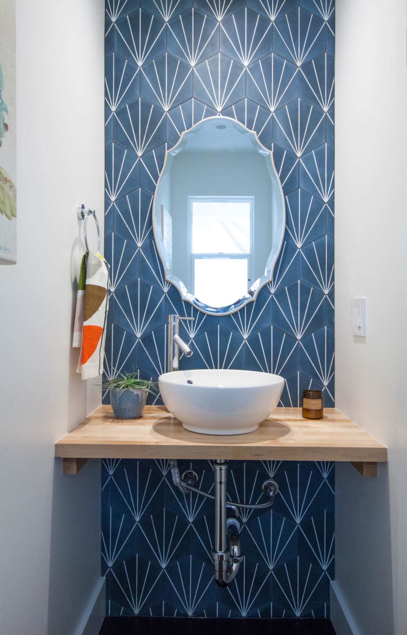 a blue and white tiled bathroom with a sink and mirror.