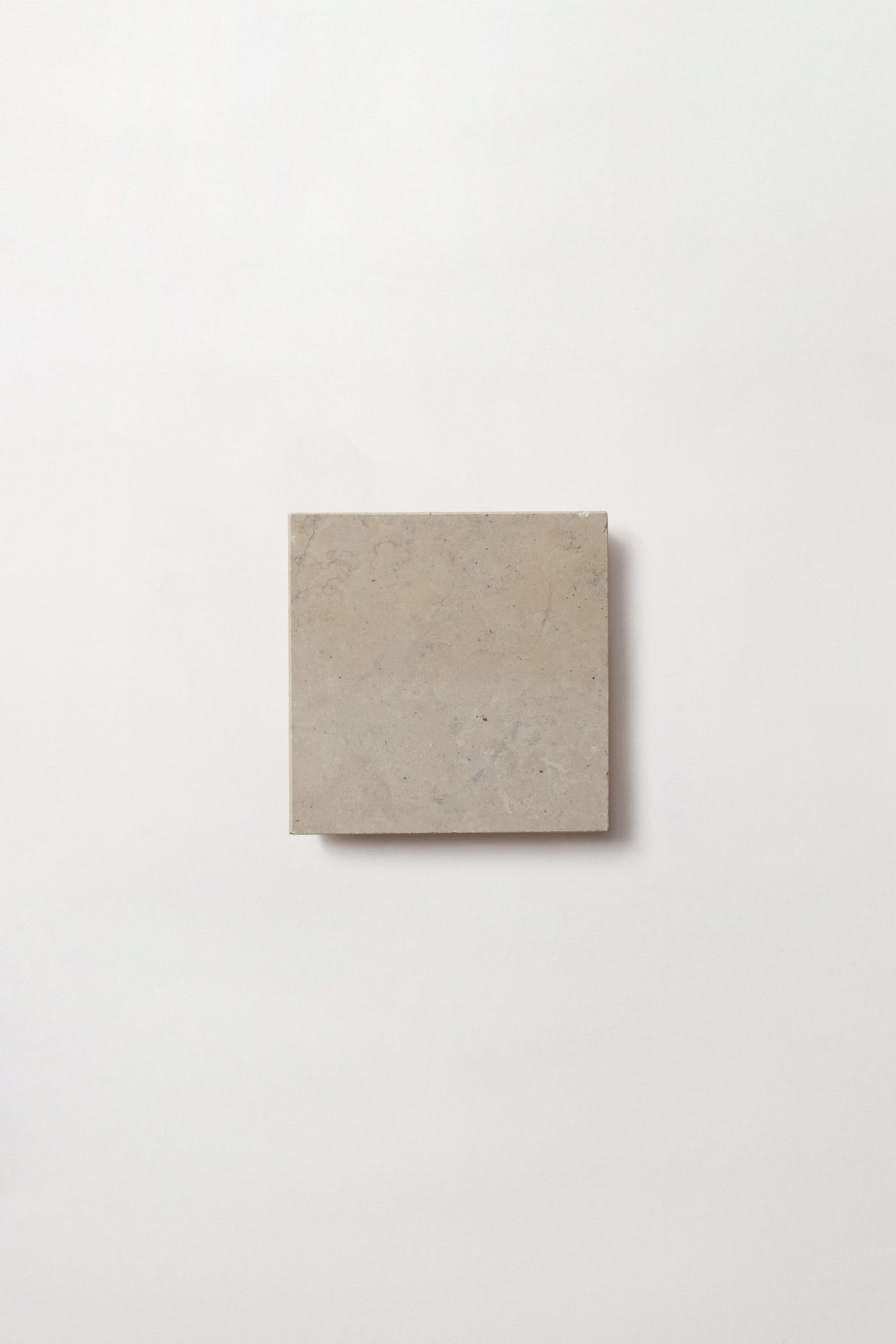 a square grey limestone tile on a white surface.