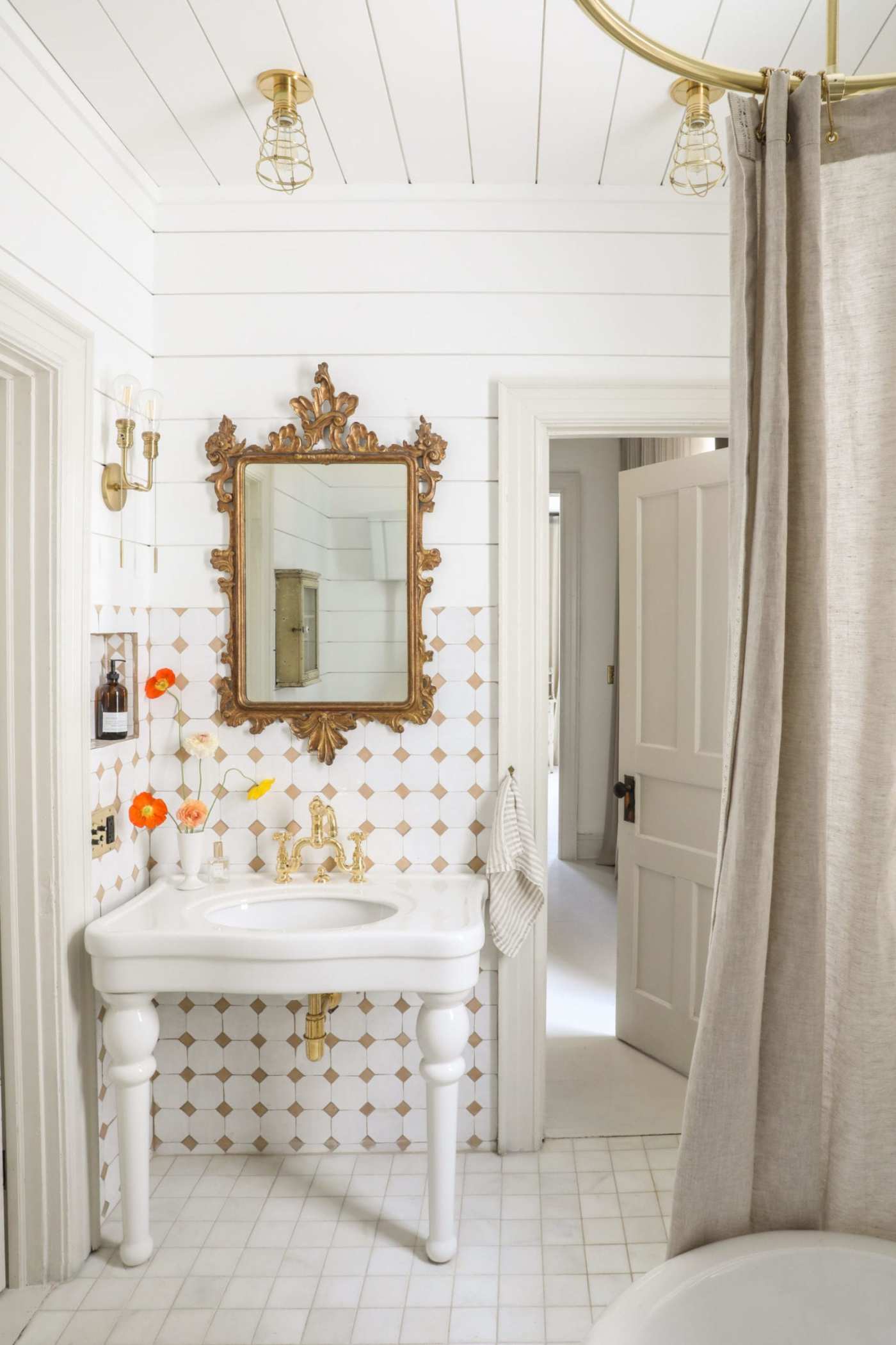 a white bathroom with a gold mirror.