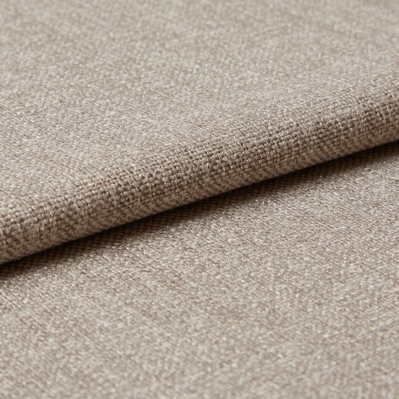 Beige woven upholstery fabric (tight basket weave), folded over an edge, displaying textured threads and slight sheen; close-up on a flat surface under soft, diffused lighting.