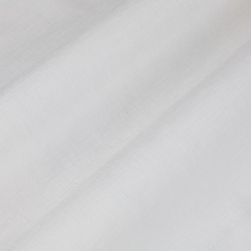 White sheer linen curtain, diagonally folded with visible weave, draping and softly filtering daylight; fills a neutral interior space with diffuse light and subtle shadows.