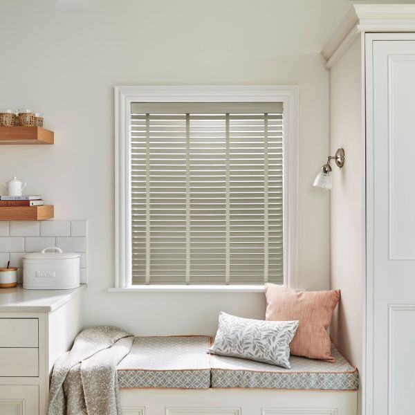 Horizontal slatted Venetian blinds (inside-mounted, beige-grey slats) closed, filtering soft daylight into a bright kitchen window seat with cushions, built-in bench, shelves, and pale walls.
Transcription: BREAD
TASTING ROME
THE PIG