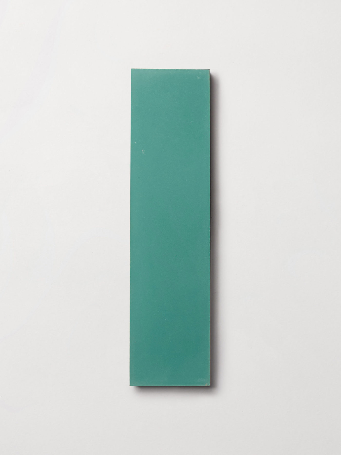 a turquoise colored rectangle tile on a white surface.