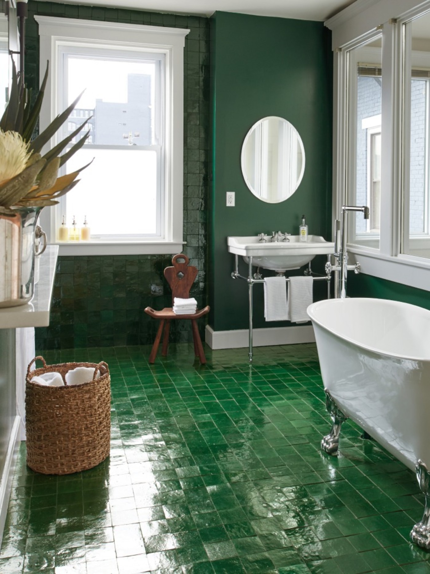 a bathroom with green tile floors and a white tub.