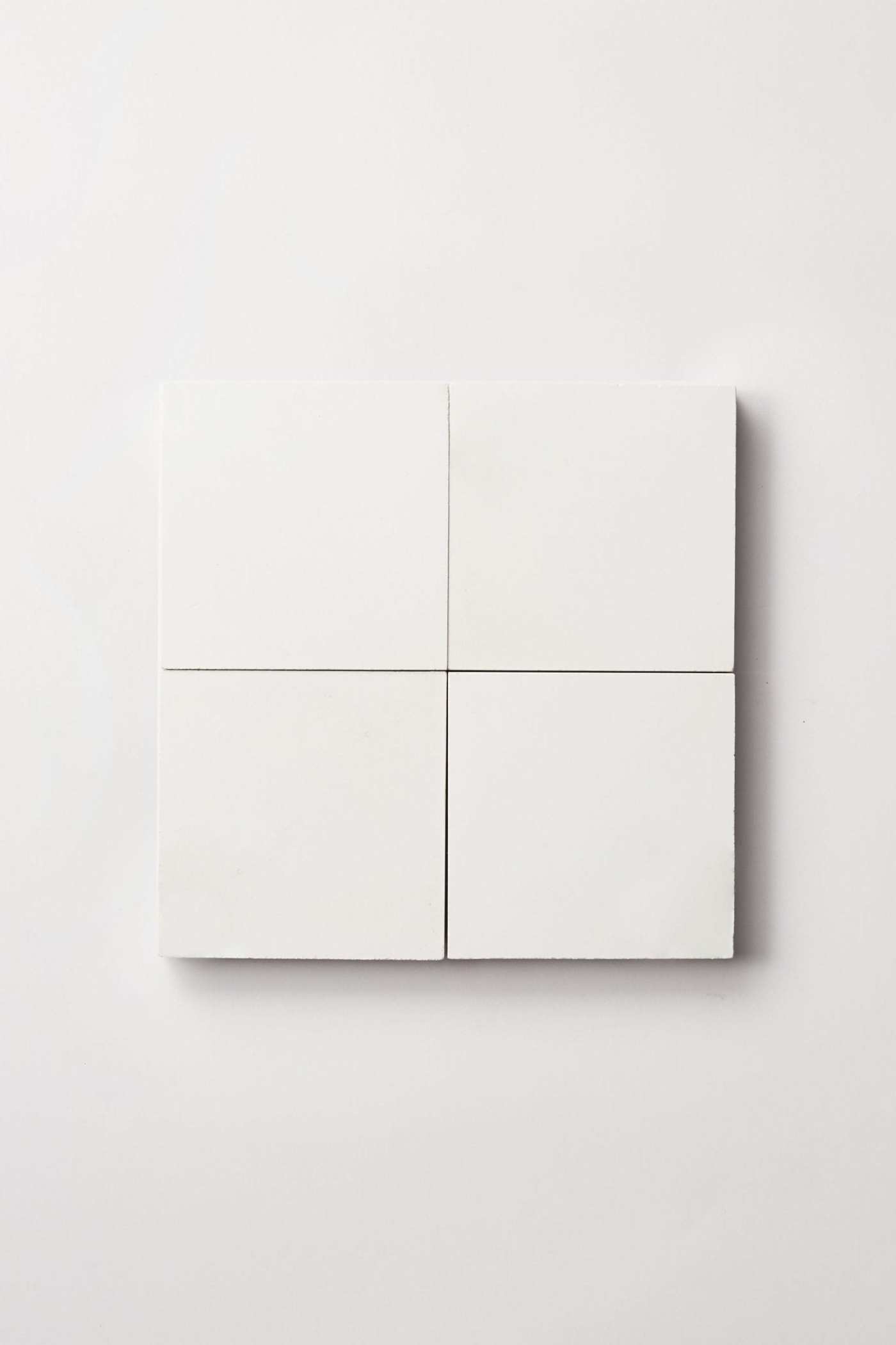 four white square tiles on a white surface.