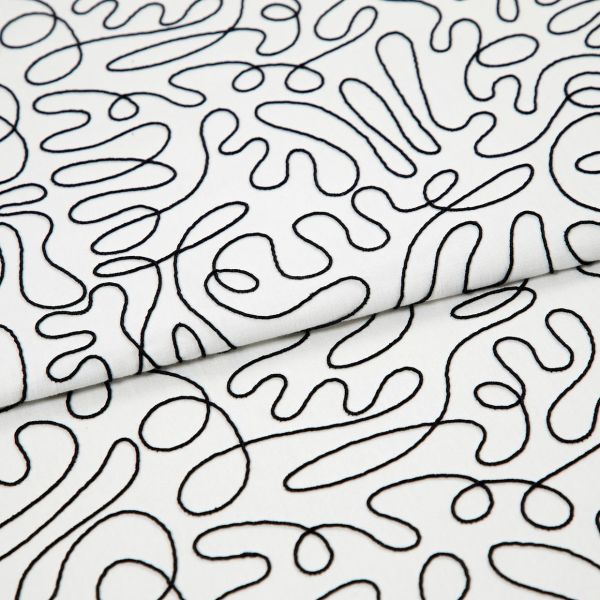 White cotton fabric with continuous black embroidered squiggle pattern, folded once and overlapping; resting flat, showing stitched loops and curves under even studio lighting as a close-up textile sample.