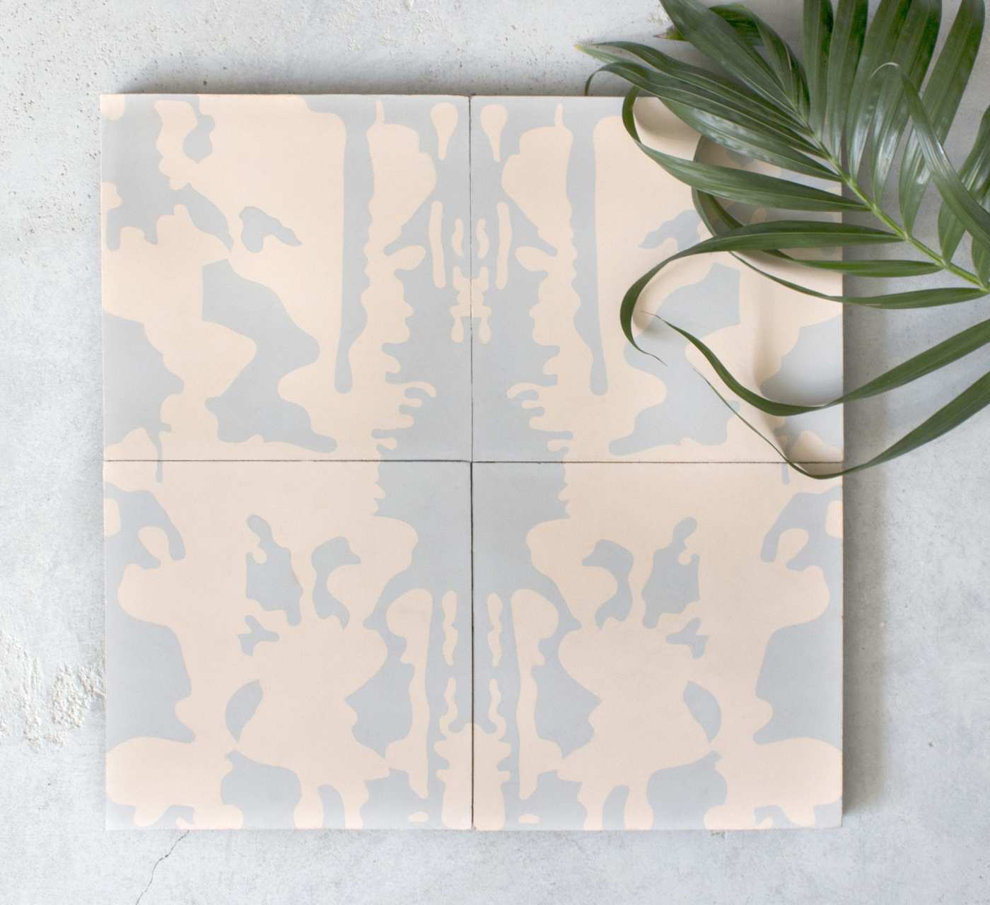 a set of tiles with a pink and grey pattern next to a plant.