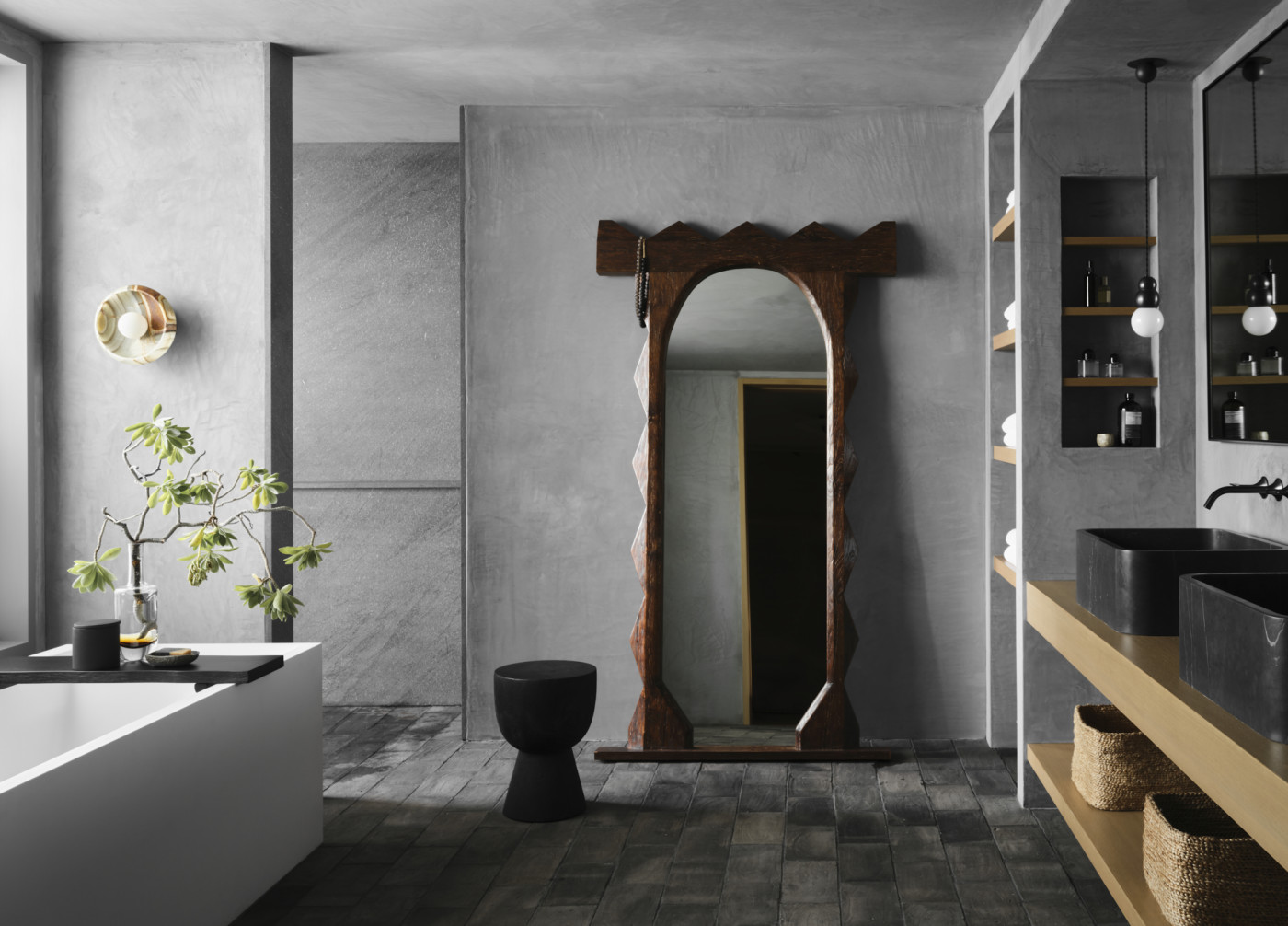 a bathroom with a large mirror, a grey tile floor, and a white tub.