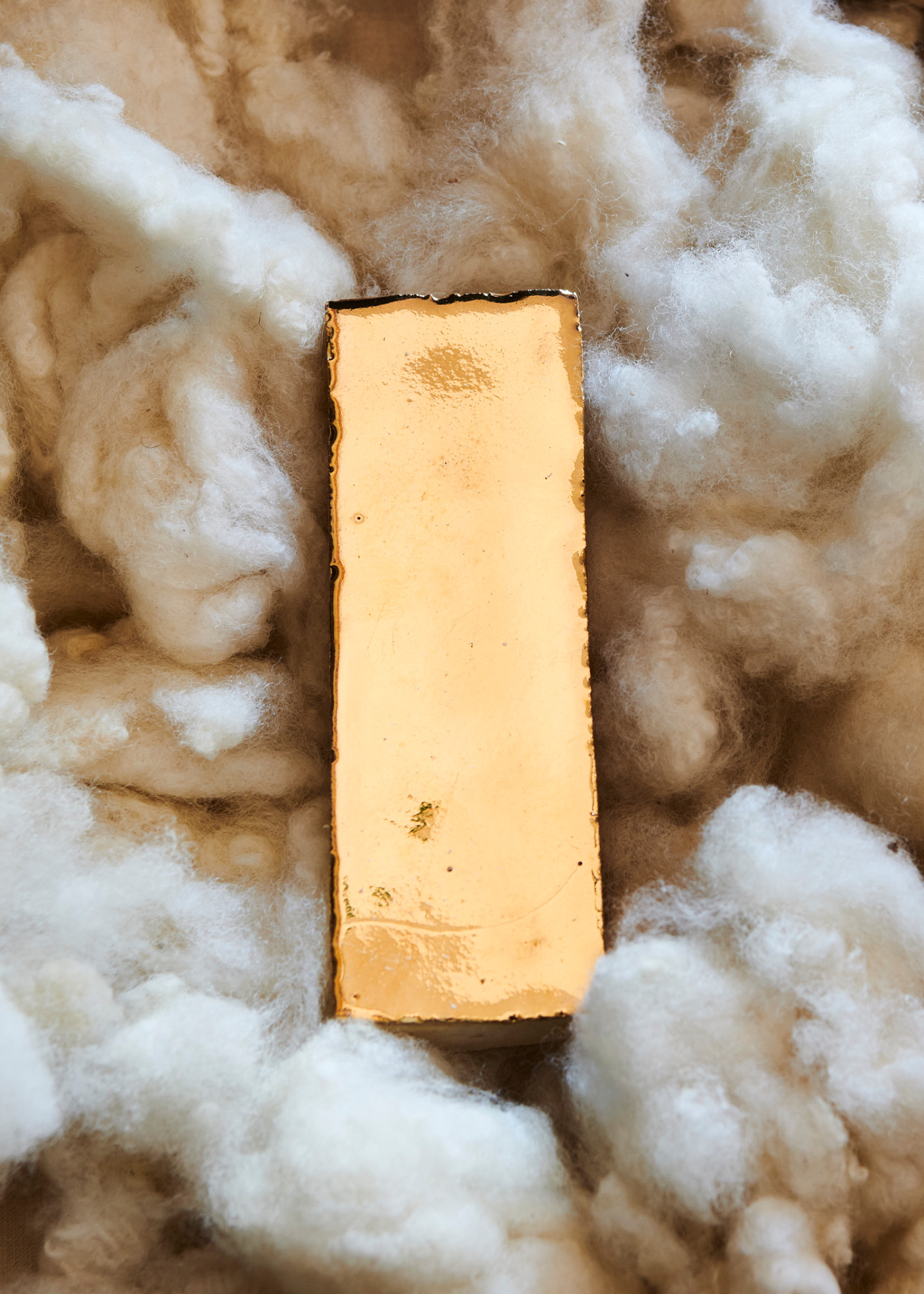 a gold tile laying on a pile of cotton.