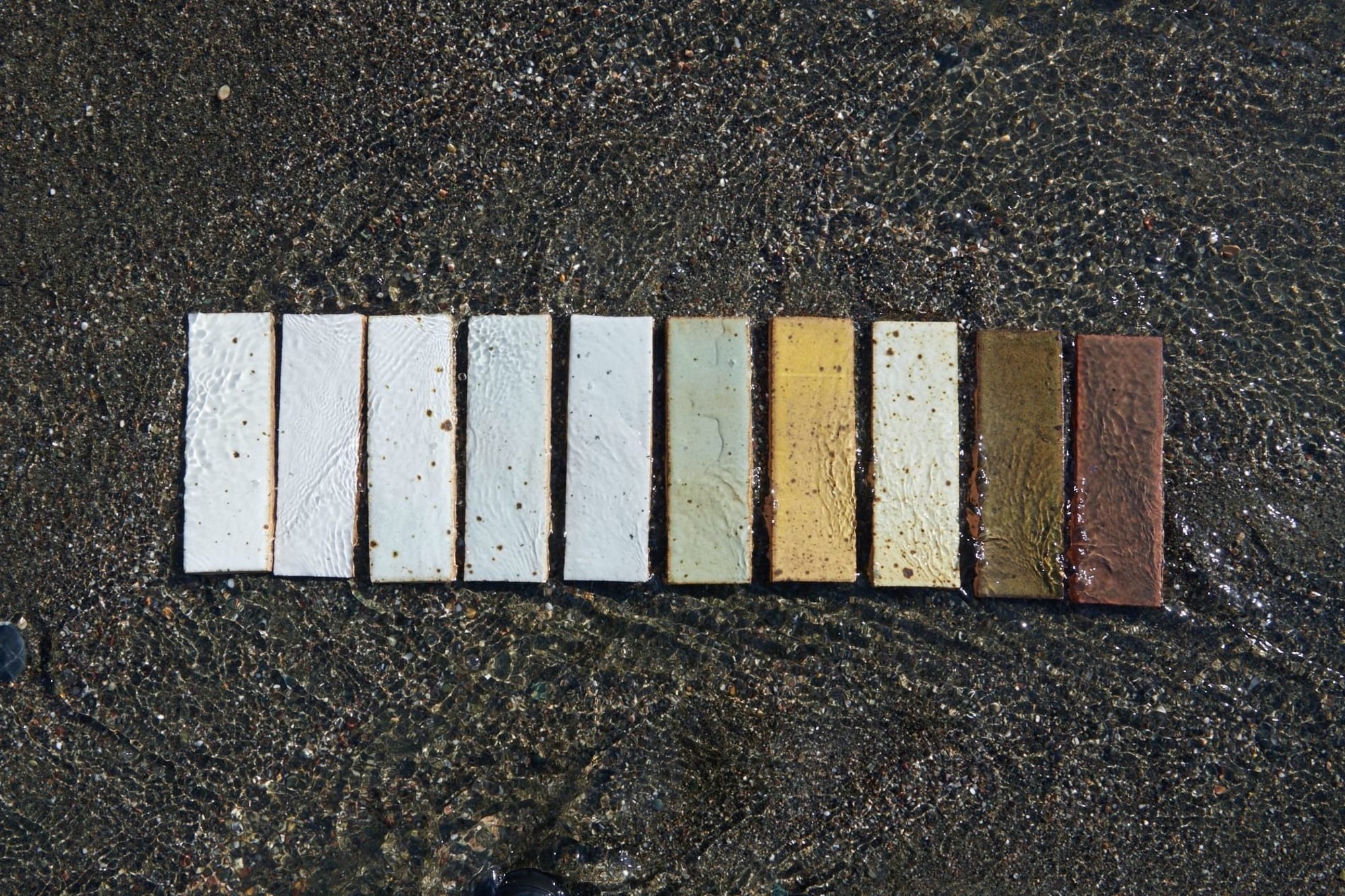 a row of multicolored tiles in the sand.