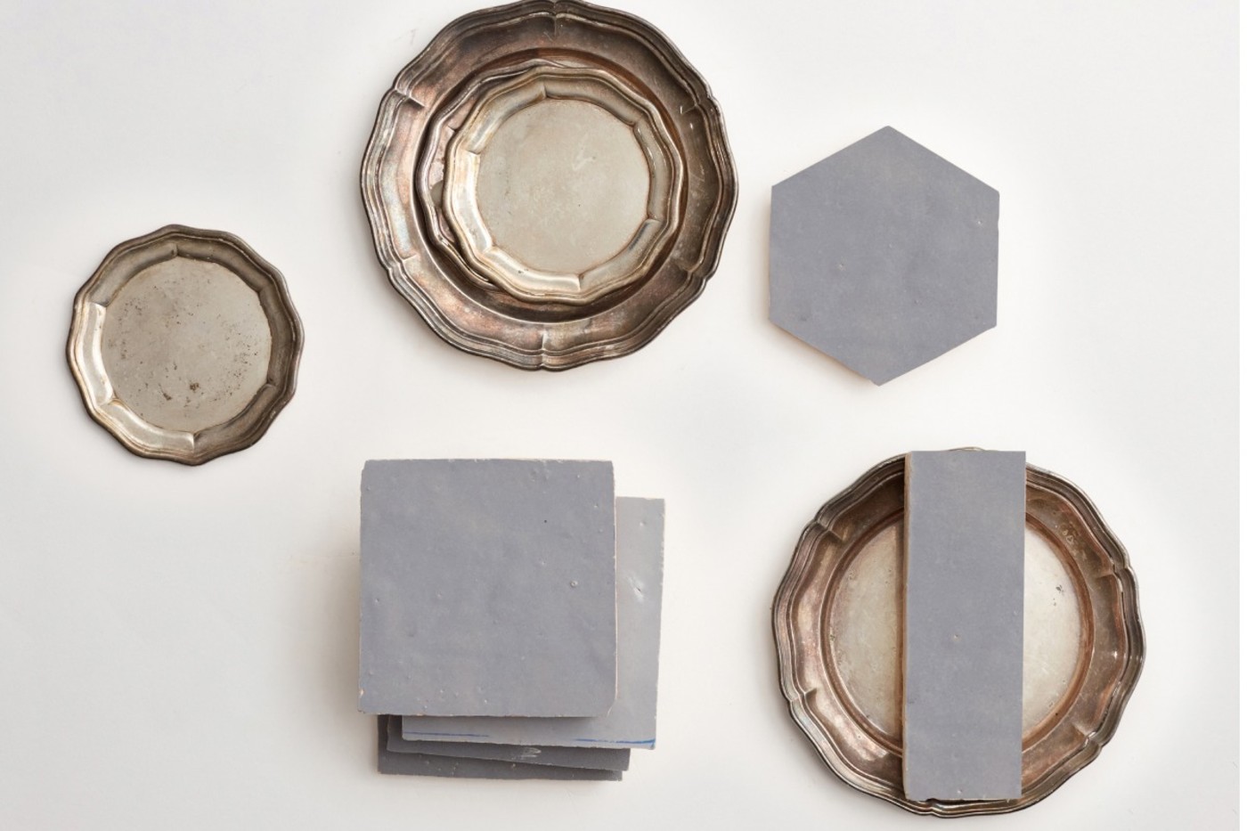 grey tiles and silver plates on a white surface.