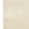 Cream-colored cellular (honeycomb) blind, fully lowered and closed, pleated horizontal cells; gently filtering diffuse light against a plain, softly lit interior with no visible window frame.