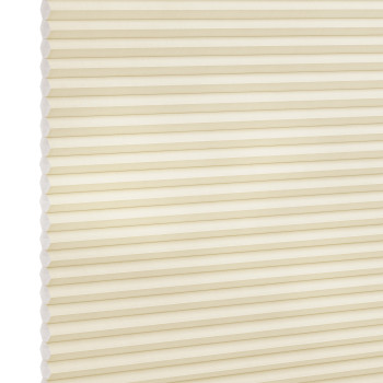 Cream-colored cellular (honeycomb) blind, fully lowered and closed, pleated horizontal cells; gently filtering diffuse light against a plain, softly lit interior with no visible window frame.