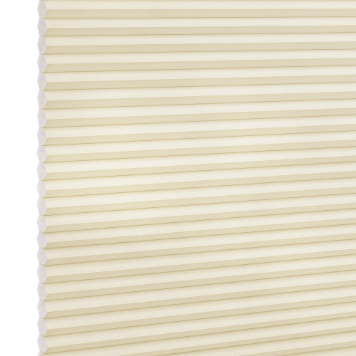 Cream-colored cellular (honeycomb) blind, fully lowered and closed, pleated horizontal cells; gently filtering diffuse light against a plain, softly lit interior with no visible window frame.