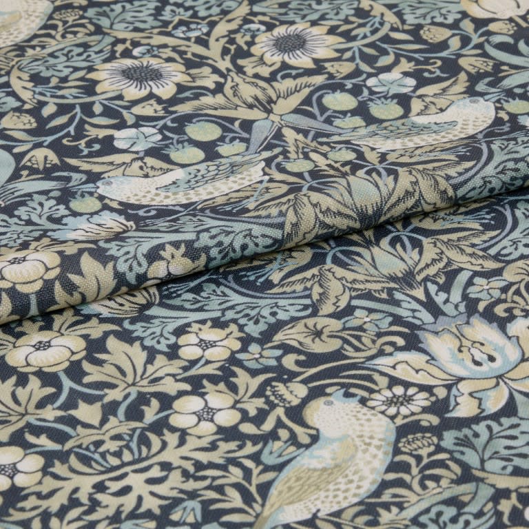A folded upholstery fabric panel with bird-and-floral tapestry print; folded over itself, revealing textured weave; close-up view in muted blue, cream, and sage tones.