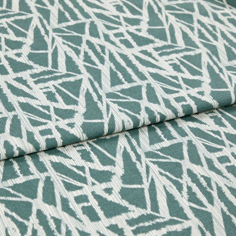 Folded teal-and-white fabric with angular abstract geometric print, folded across the center, showing overlapping layers and ribbed weave; close-up on a flat surface under soft, even lighting.