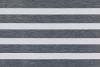 Zebra-style roller blind with alternating opaque white and semi-transparent dark-gray textured horizontal bands; bands aligned to create alternating blocked and filtered light; covers a window in a neutral, evenly lit interior.