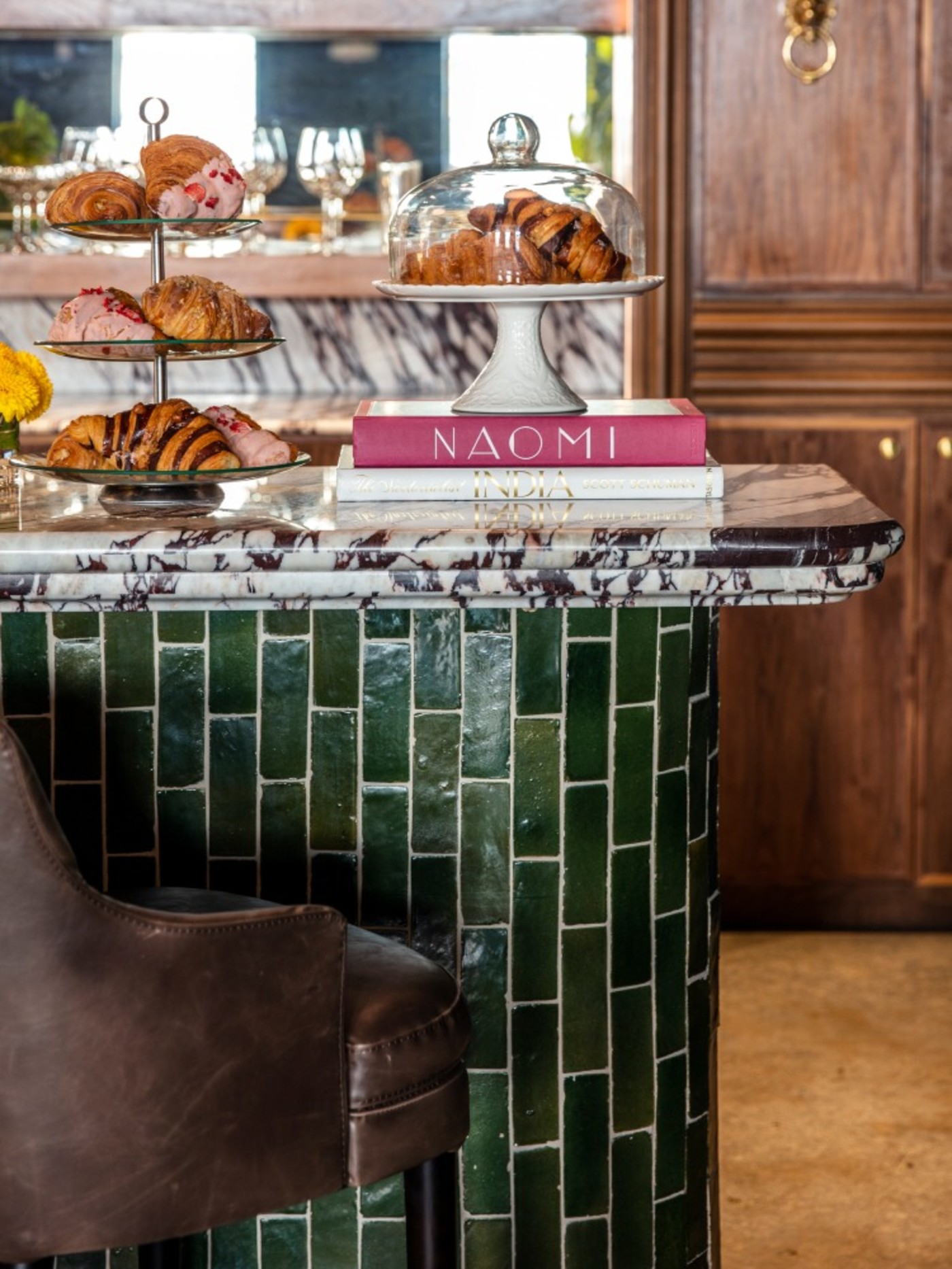 a green tiled kitchen island with a stool.