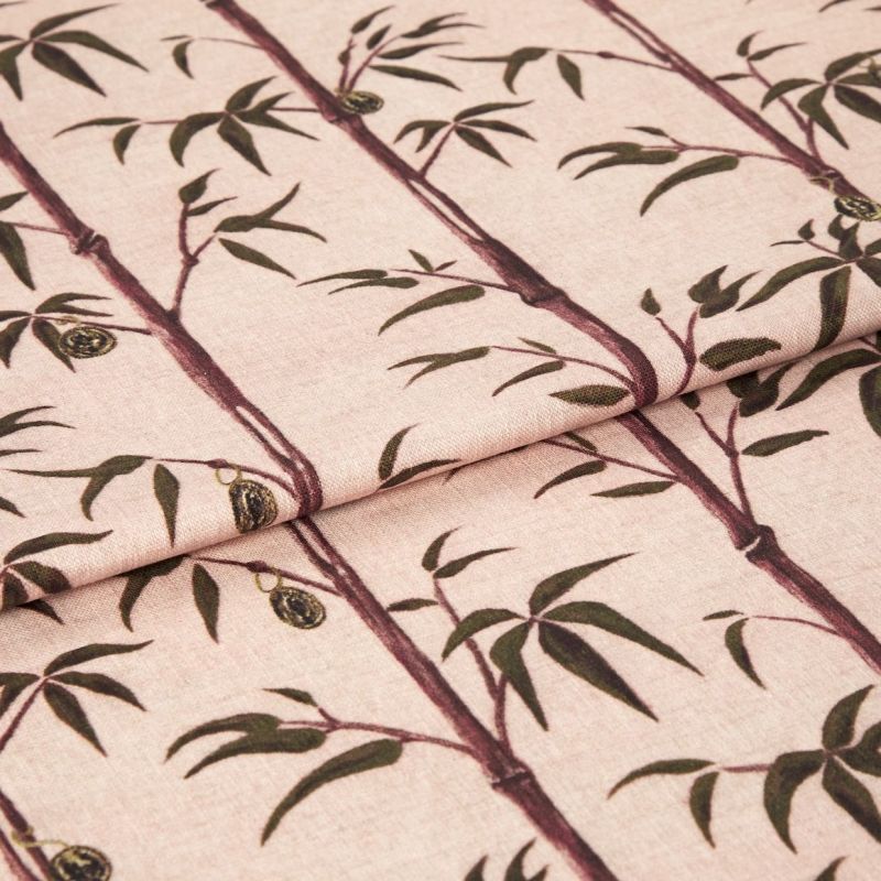 Folded fabric sample in blush pink background with linear print of bamboo shoots and leaves.