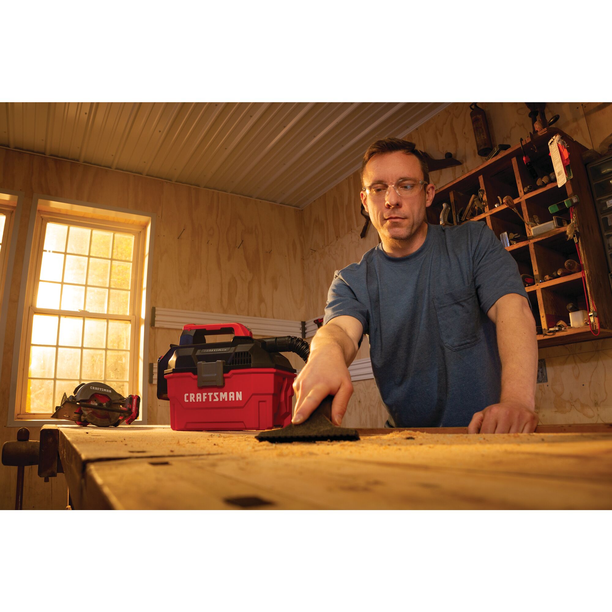 20 volt cordless 2 gallon wet dry vacuum being used by a person to clean wooden work station.