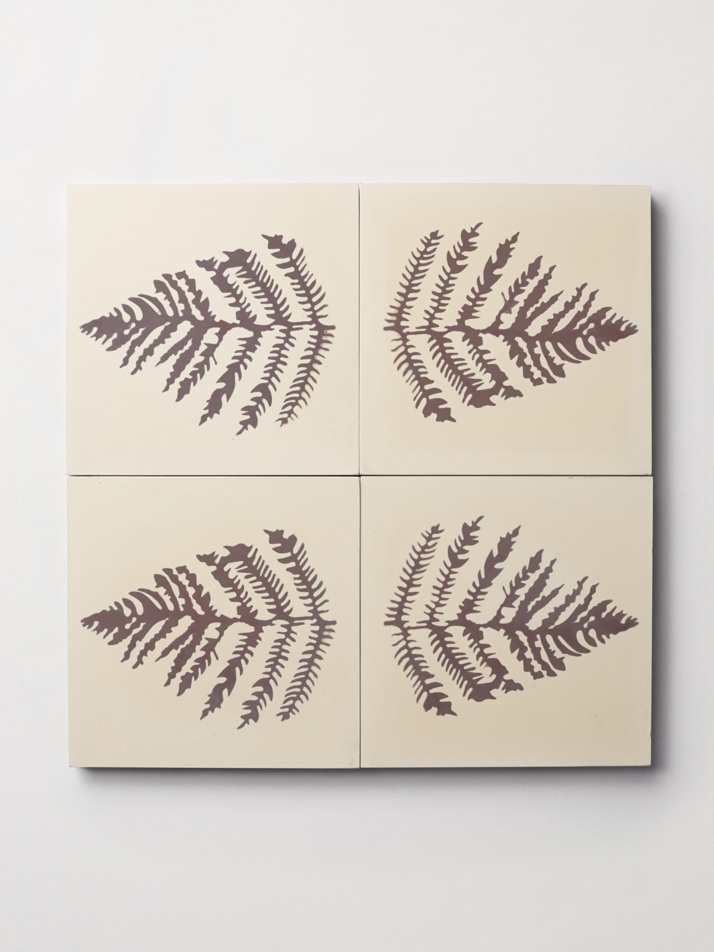 four white tiles with fern leaf prints on them.