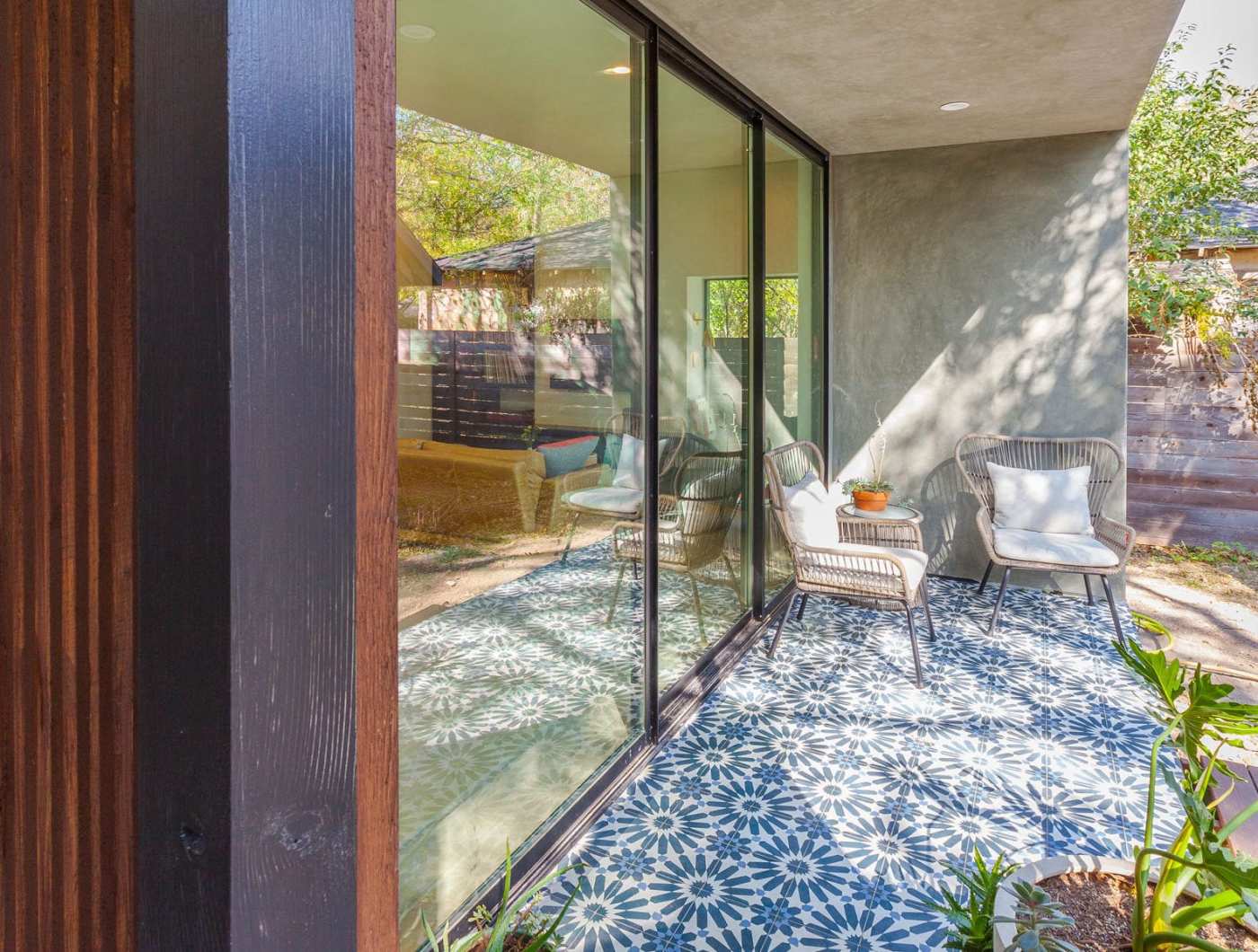 a patio with a sliding glass door and a blue and white tiled floor.