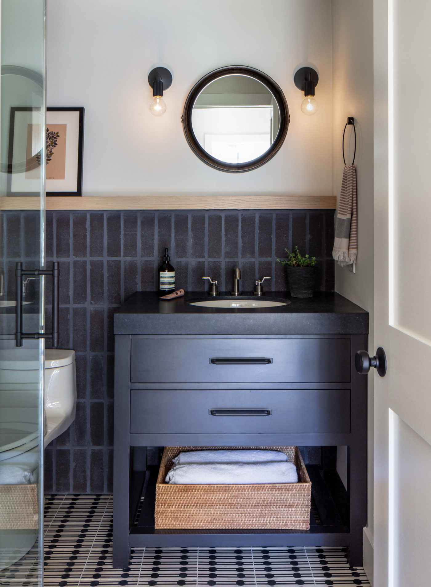 a black and white bathroom with a sink and mirror.