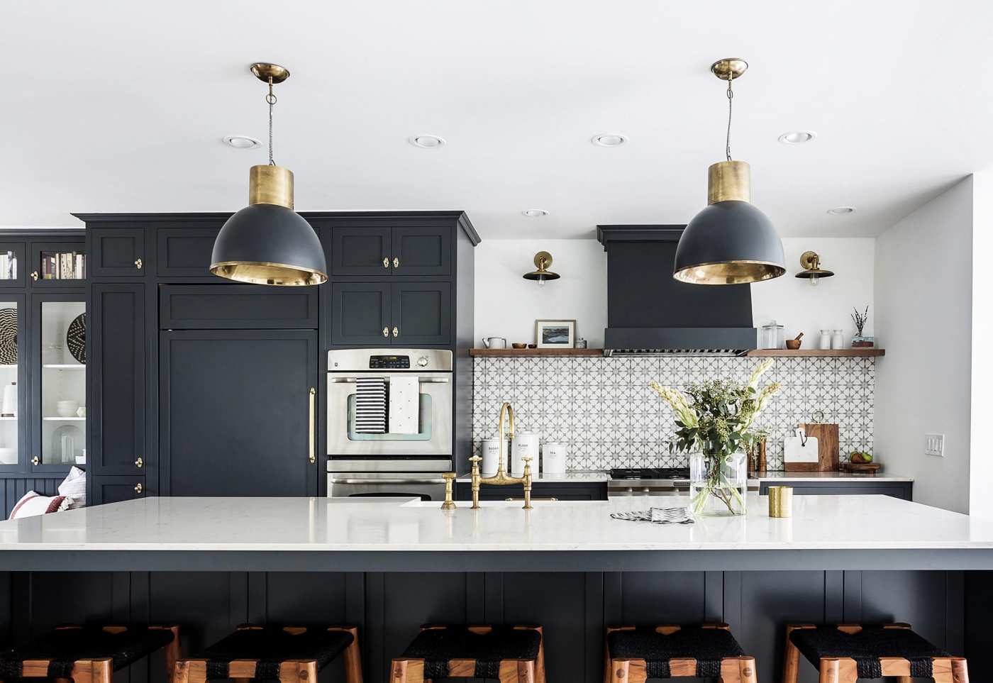 a kitchen with black cabinets and stools.