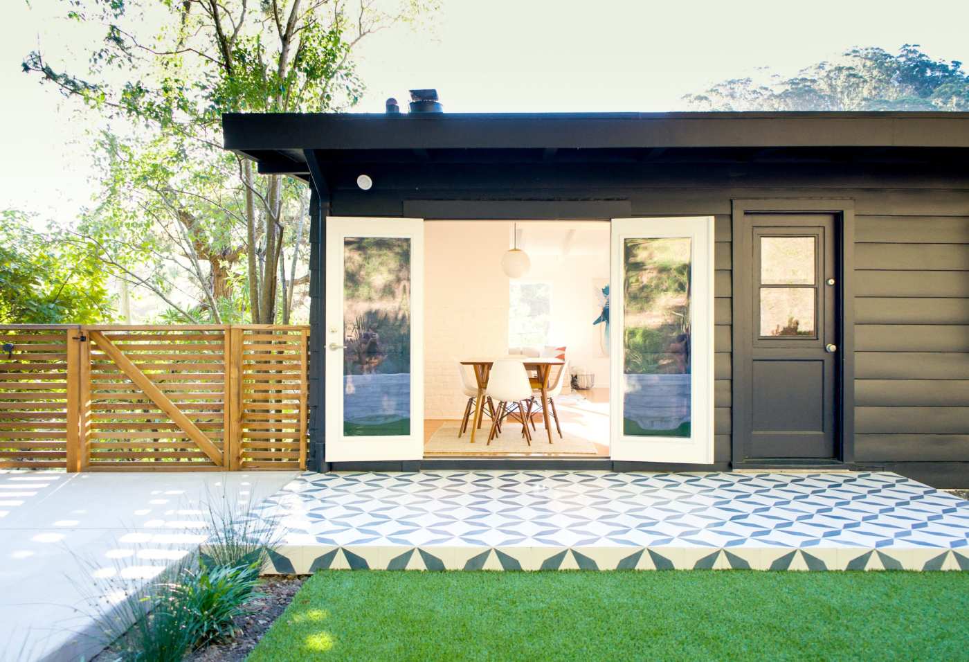 a small black house with a tiled patio.