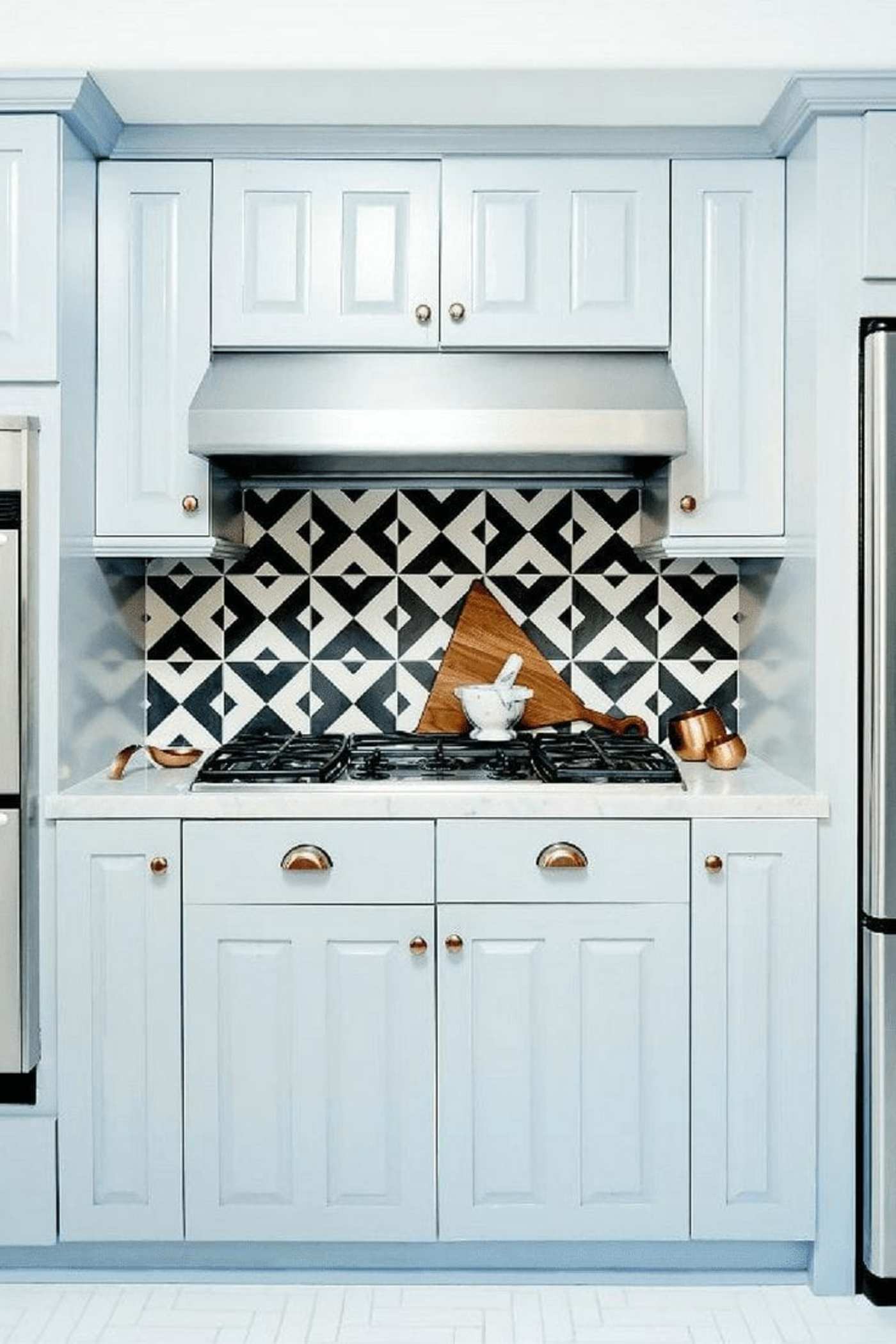 a kitchen with blue cabinets and a black and white tiled backsplash.